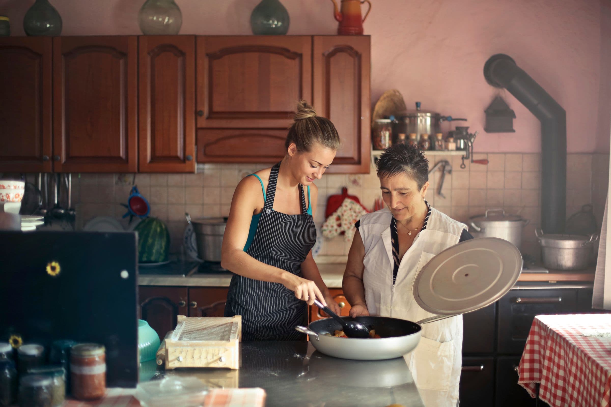 A caregiver and an older woman cooking a meal together in her kitchen.